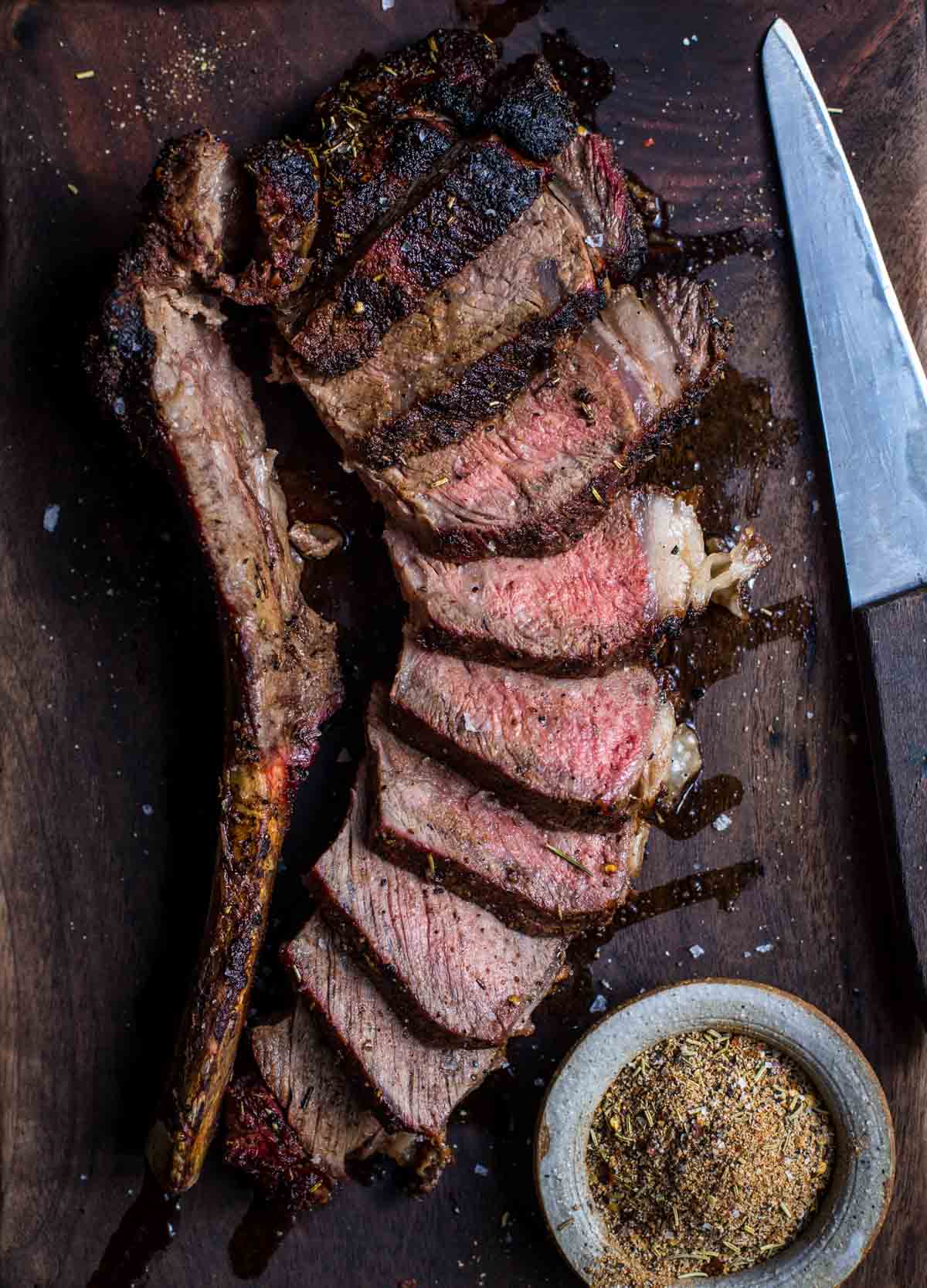 Sliced tomahawk steak on a cutting board.