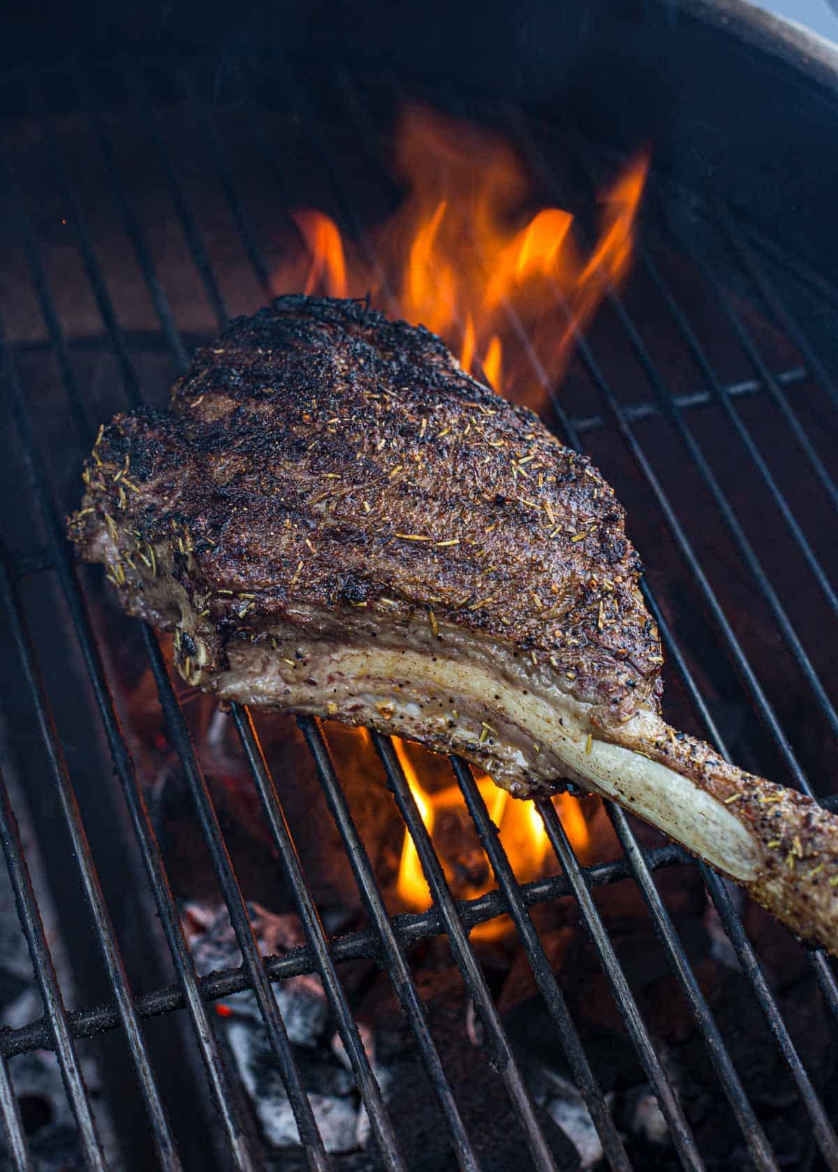 Tomahawk steak cooking over direct heat on a Big Green Egg.