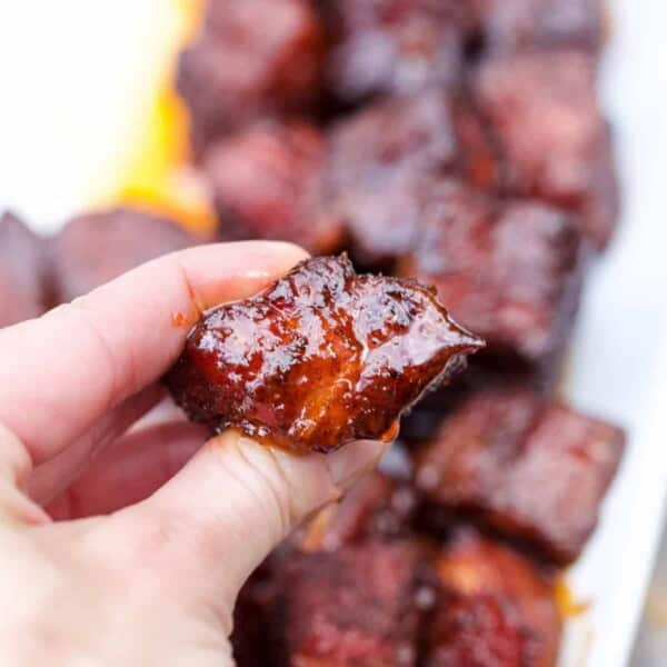 A cube of pork belly burnt ends with sauce.