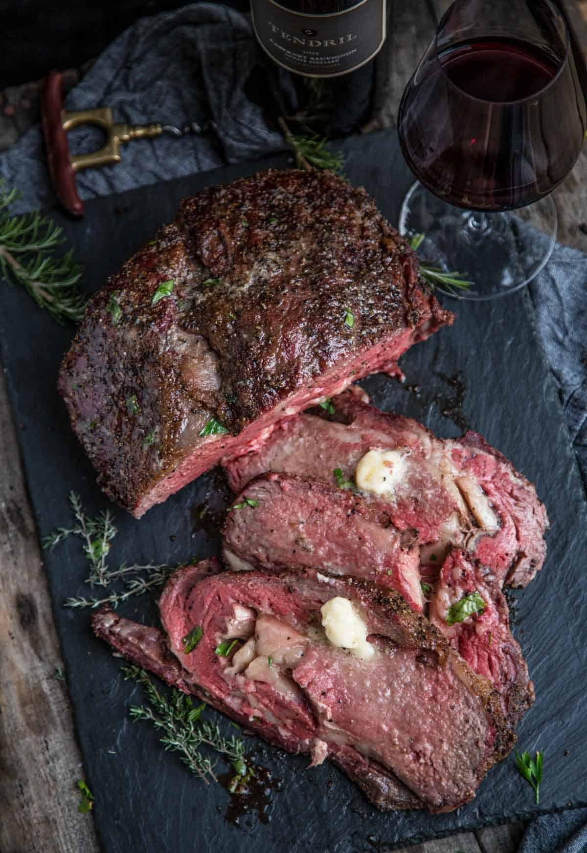 Slices of Prime Rib roast on a slate plate topped with horseradish butter.