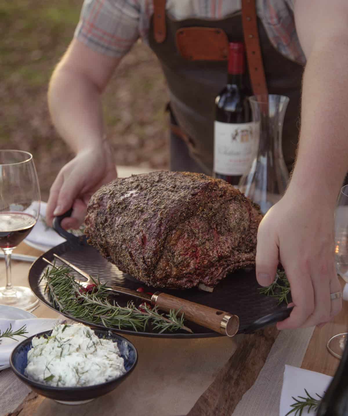 Setting a smoked prime rib on a dinner table surrounded by holiday side dishes