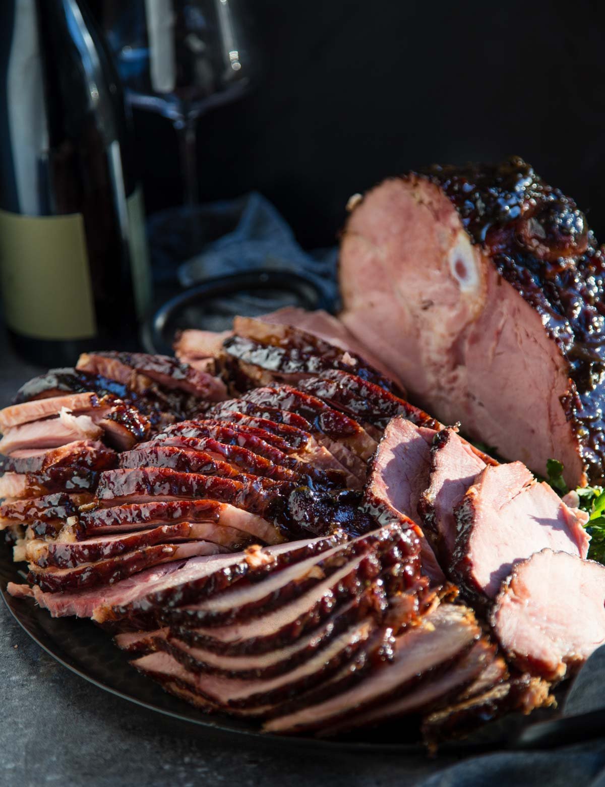 Slices of smoked ham with brown sugar glaze with a bottle of wine