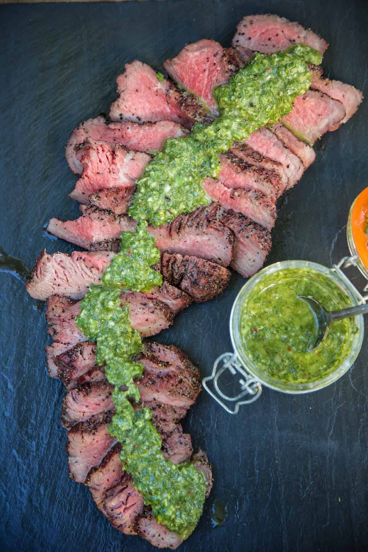 Slices of smoked Tri Tip with homemade Chimichurri sauce on tip