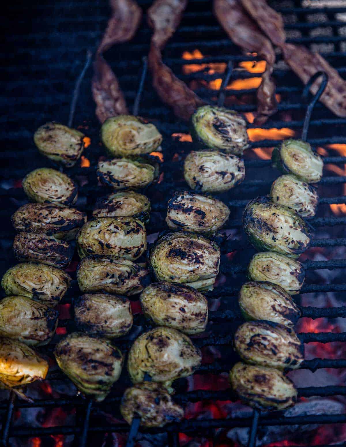 Brussels sprouts cooking on the grill on skewers with bacon 