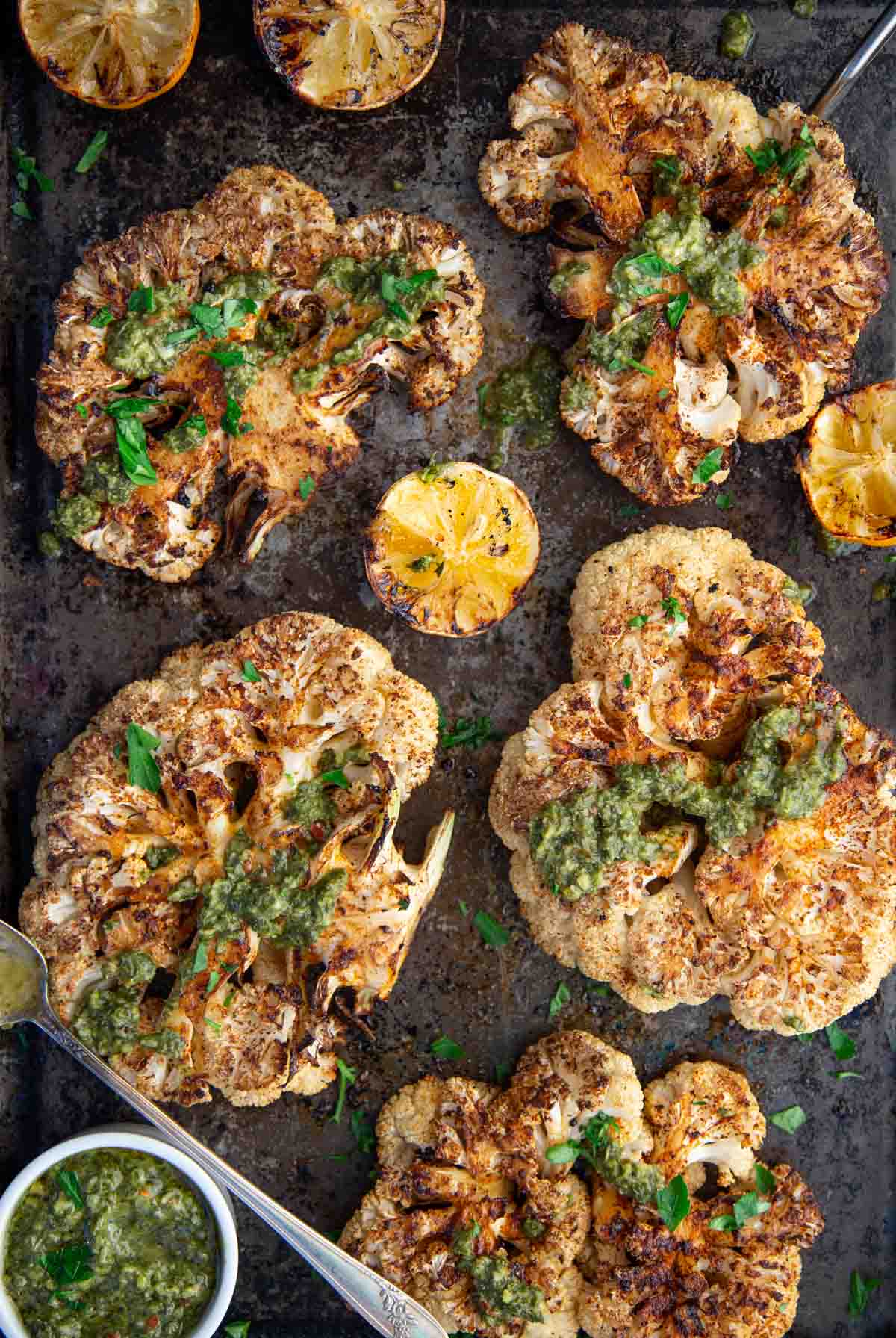 Grilled Cauliflower Steaks topped with Chimichurri sauce on a sheet pan 
