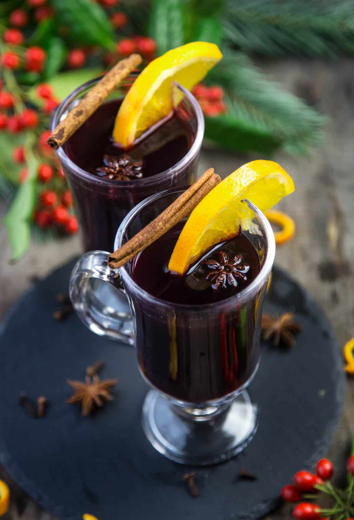 Two glasses of Easy Mulled Red Wine in serving glasses garnished with cinnamon and orange