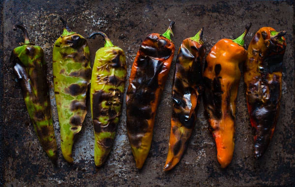 Roasted green and red chiles on a sheet pan.