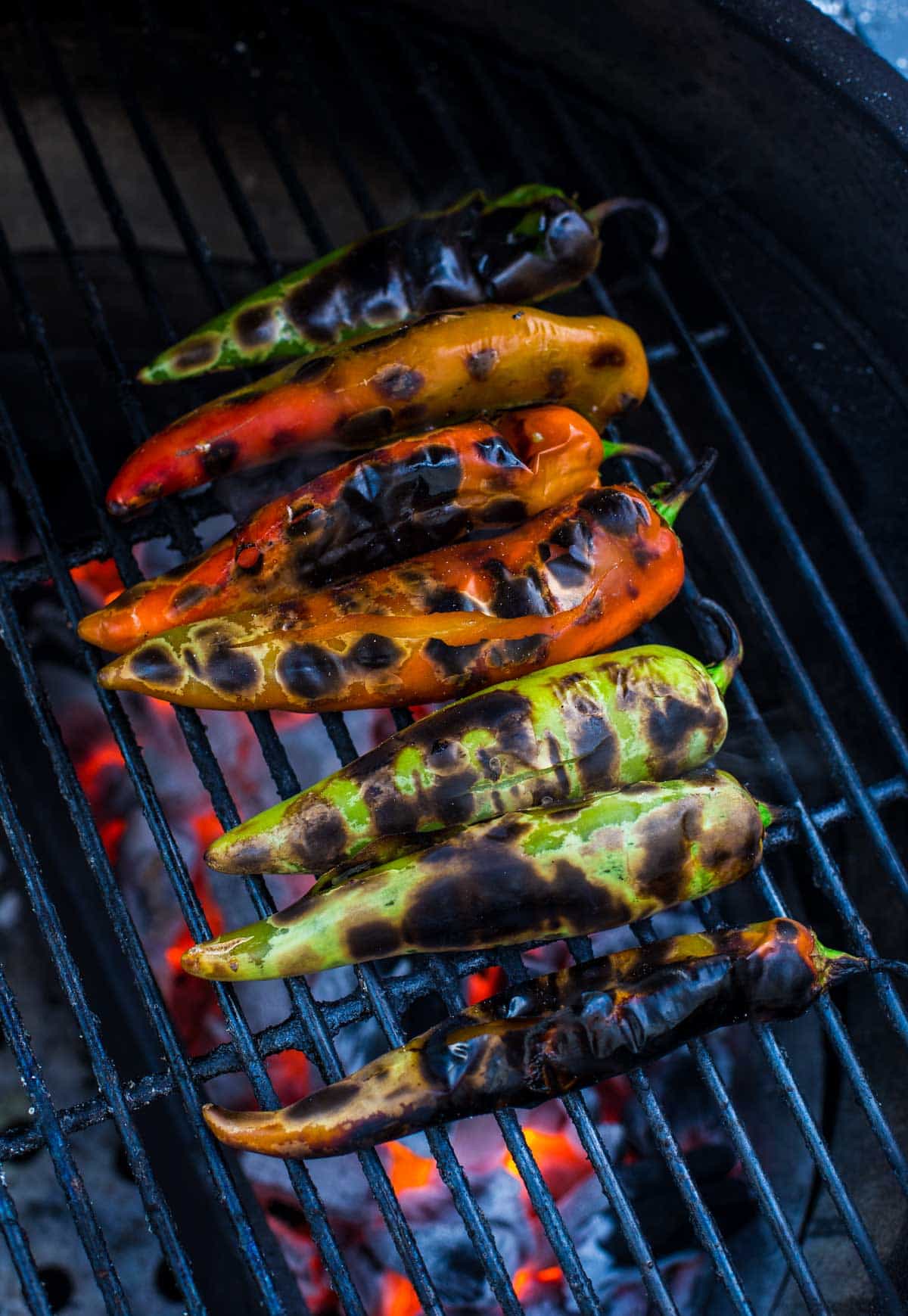 Green chile peppers grilled with blister marks ready to be pulled off.