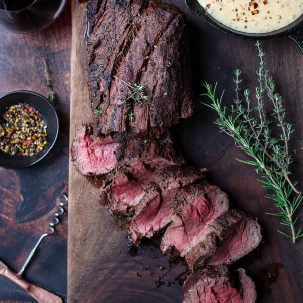 Grilled Beef Tenderloin with mustard steak sauce on cutting board.