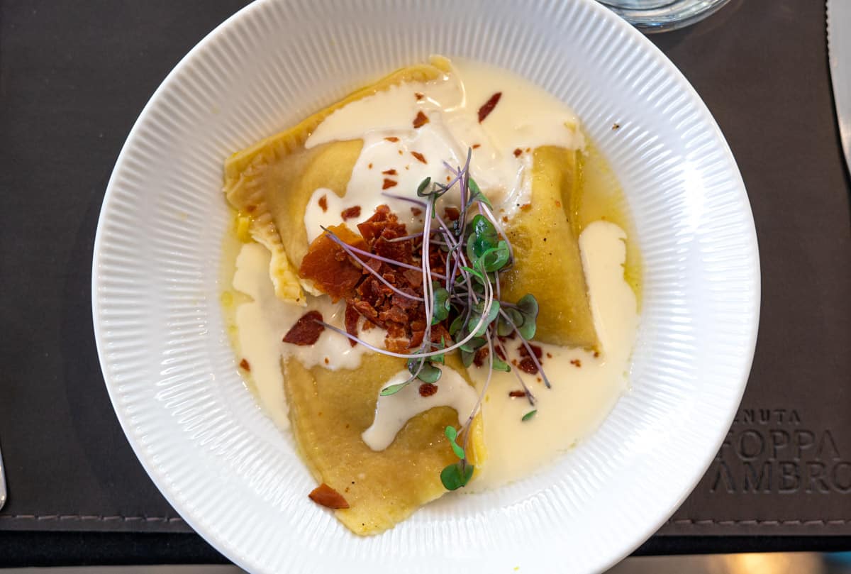 Pumpkin Ravioli with coppa and cream sauce in a bowl.