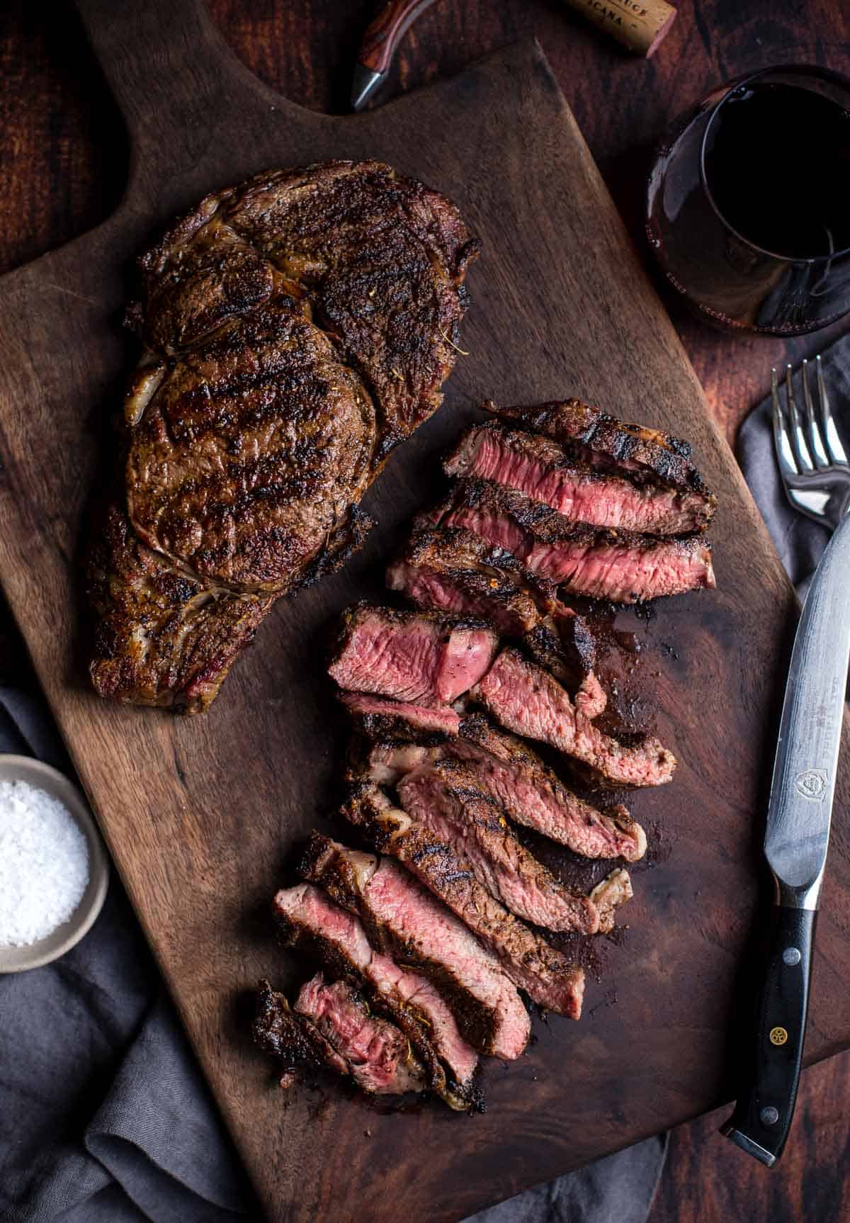 Grilled ribeye live fire steaks on a cutting board after being cooked over live fire.