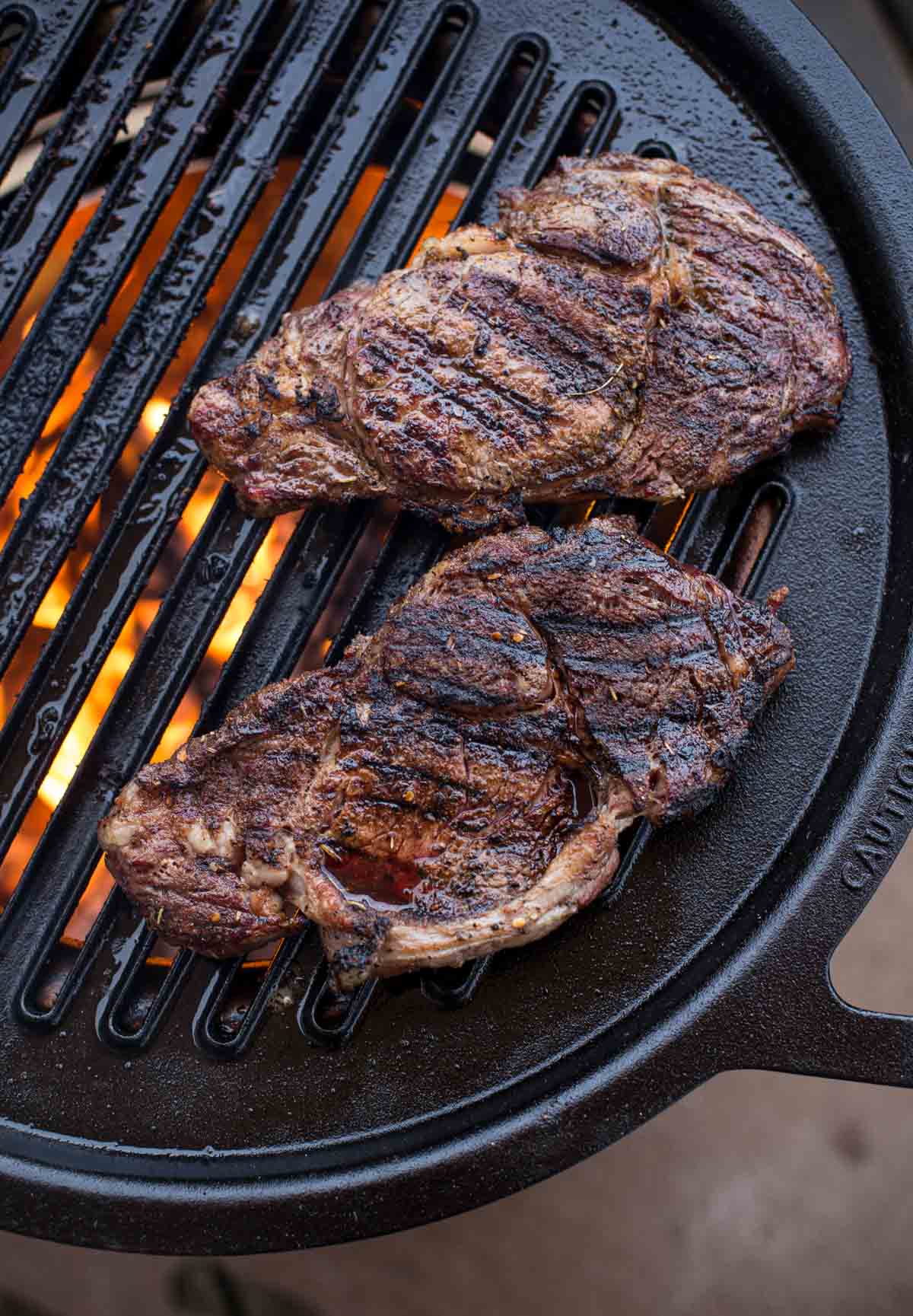 Grilled Ribeye Steaks cooking on a Solo Stove Bonfire with Hub grill grate.