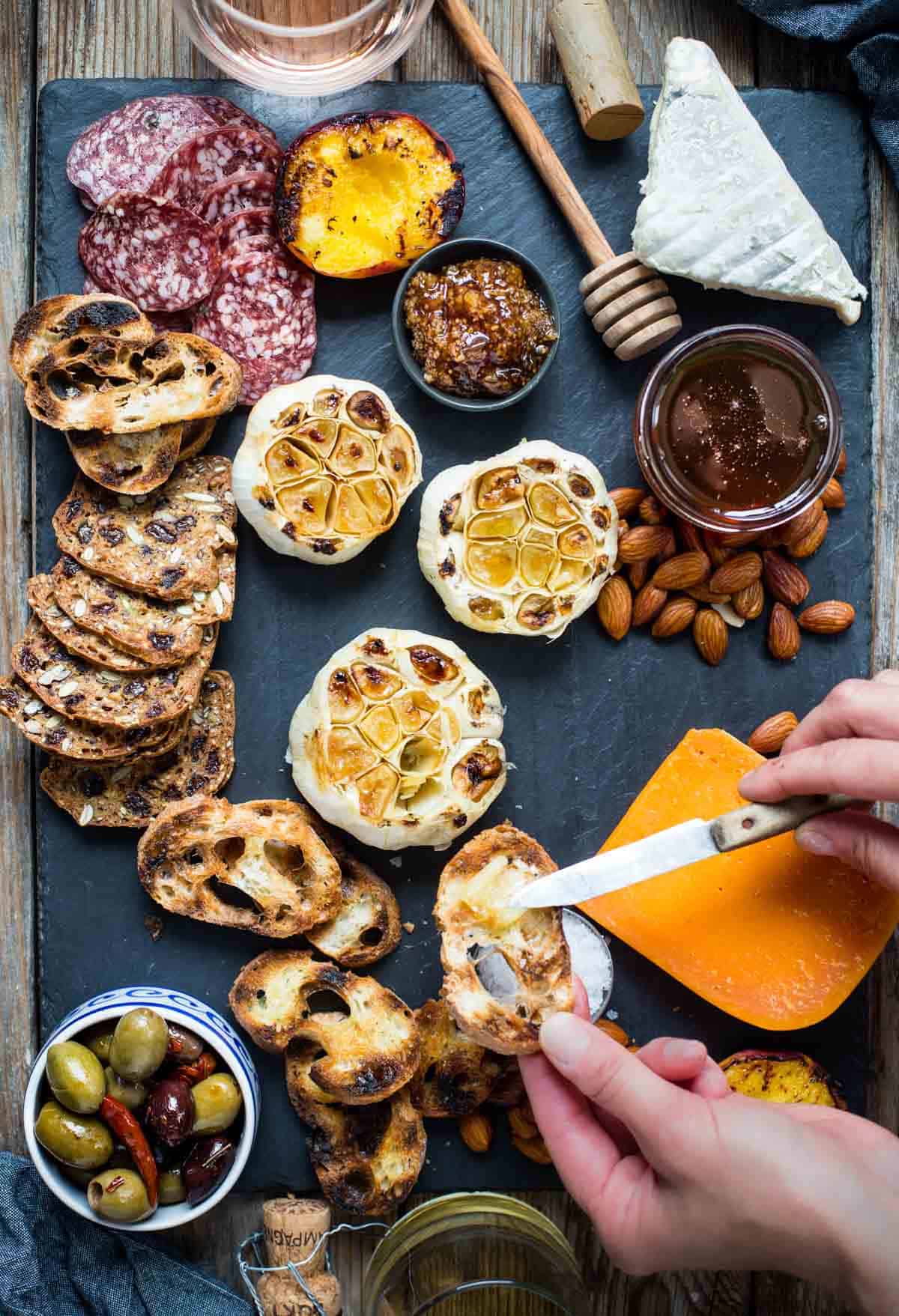 a platter with roasted garlic and spreading it over toasted baguette