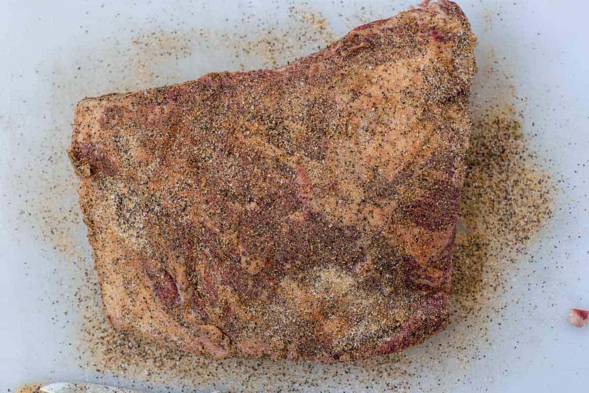 Raw beef plate ribs on a cutting board seasoned with beef seasoning 