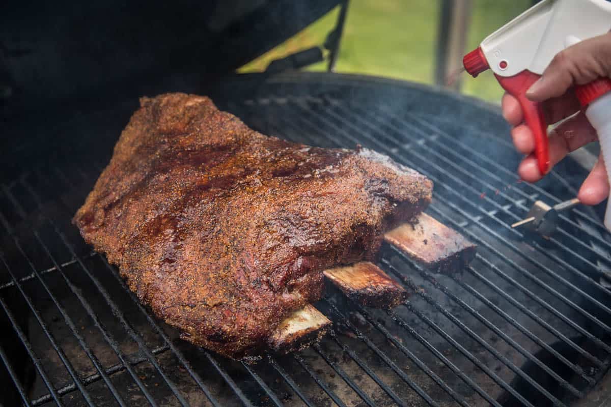 Spritzing beef ribs on the smoker