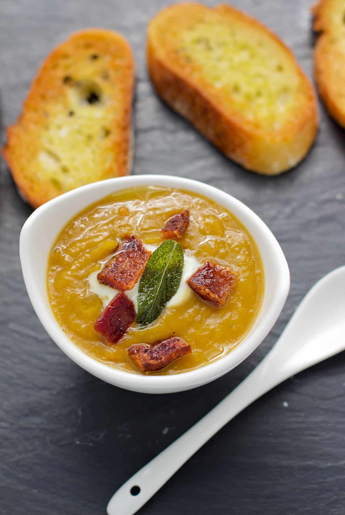 A cup of smoked butternut squash soup topped with fried sage and bacon