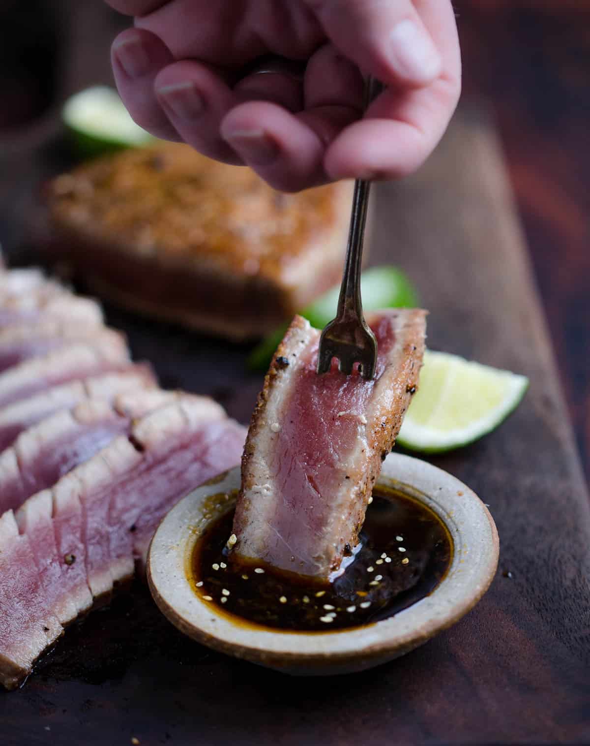 Slice of Ahi Tuna dipping in a soy dipping sauce