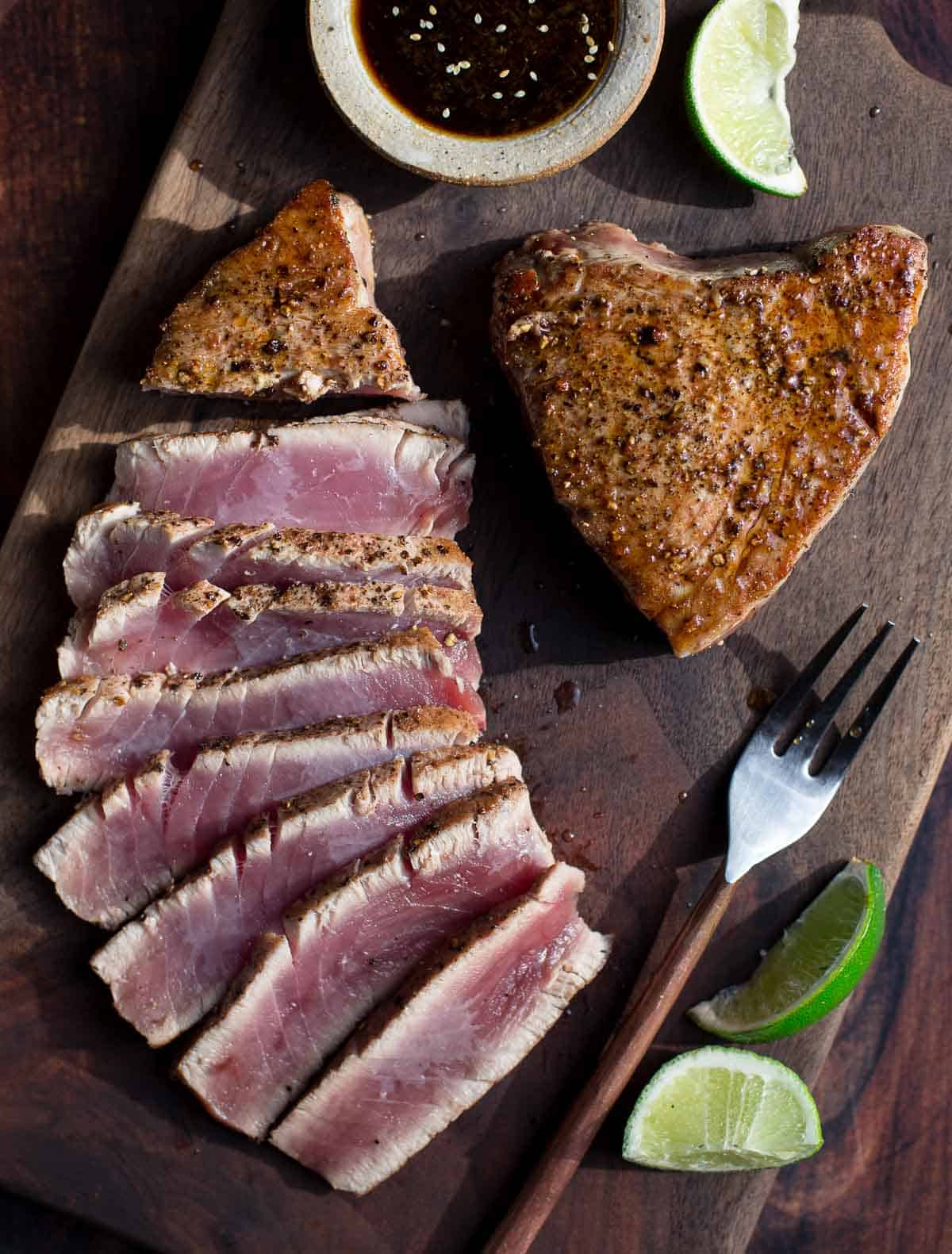 Grilled Tuna Steak on a cutting board with slices of perfectly cooked Ahi Tuna