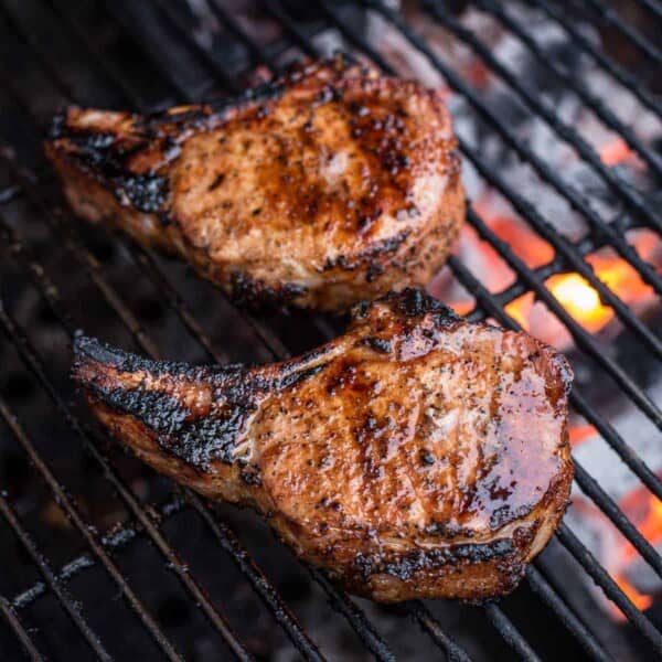 Pork tomahawk steaks being cooked over direct heat.