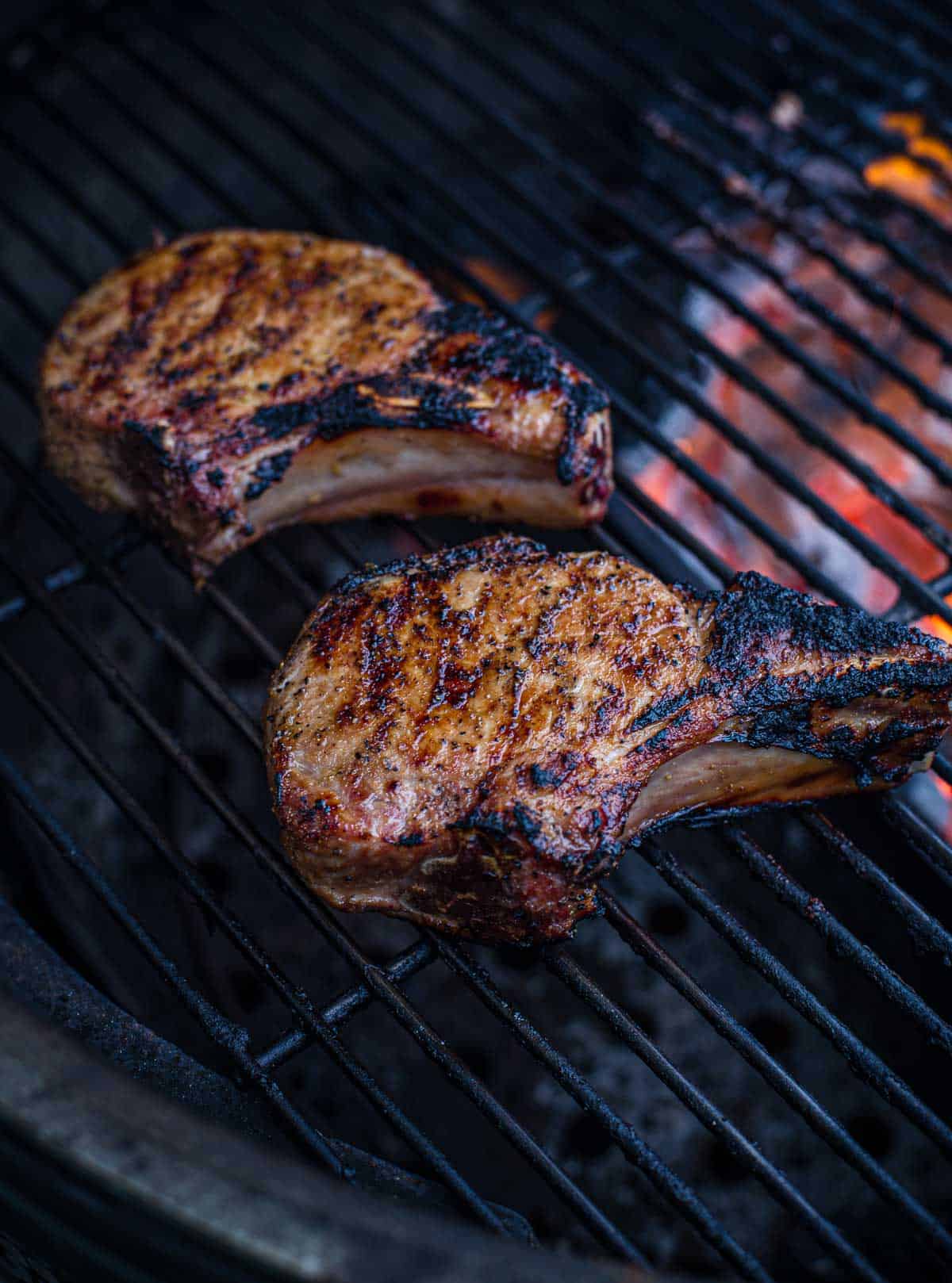 Two pork chops cooking on a big green egg grill