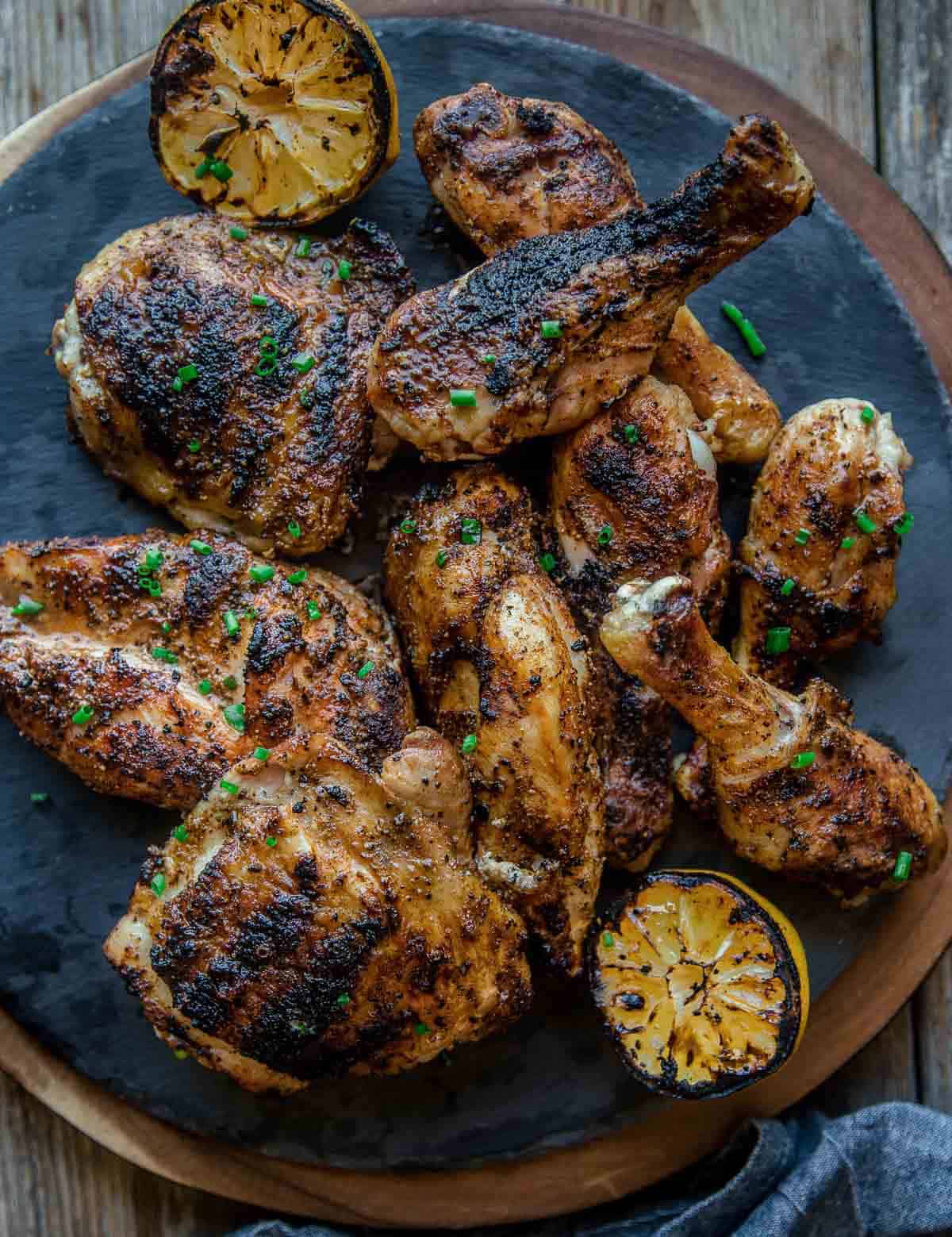 Pieces of perfectly grilled chicken on a platter with grilled lemon