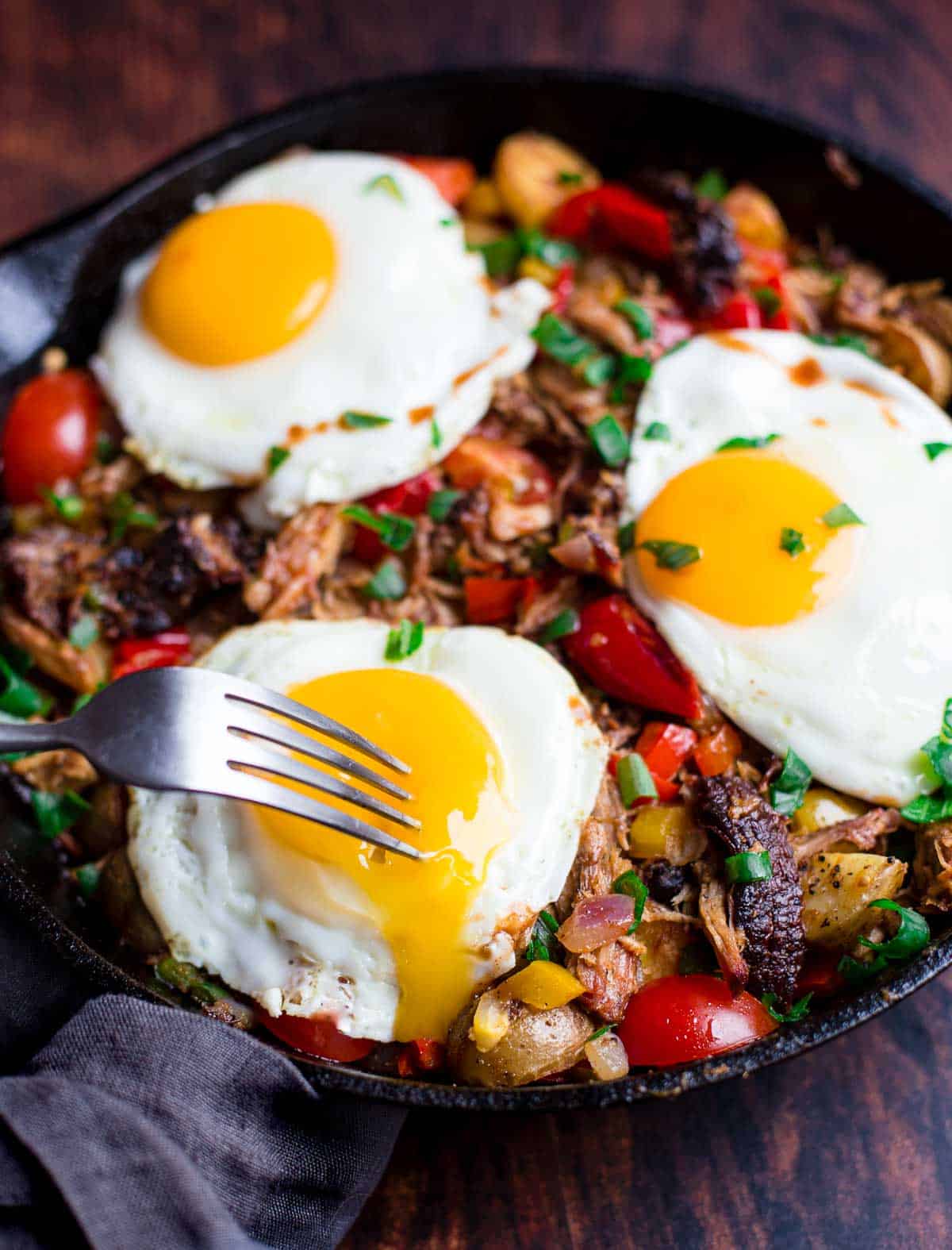 Pulled pork hash with eggs in a pan.
