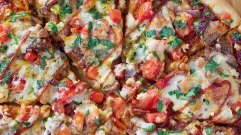 Brisket pizza sliced on a cutting board.