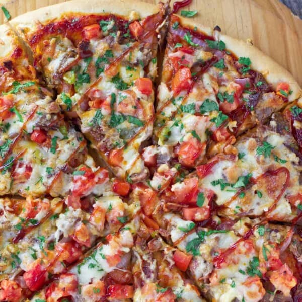 Brisket pizza sliced on a cutting board.