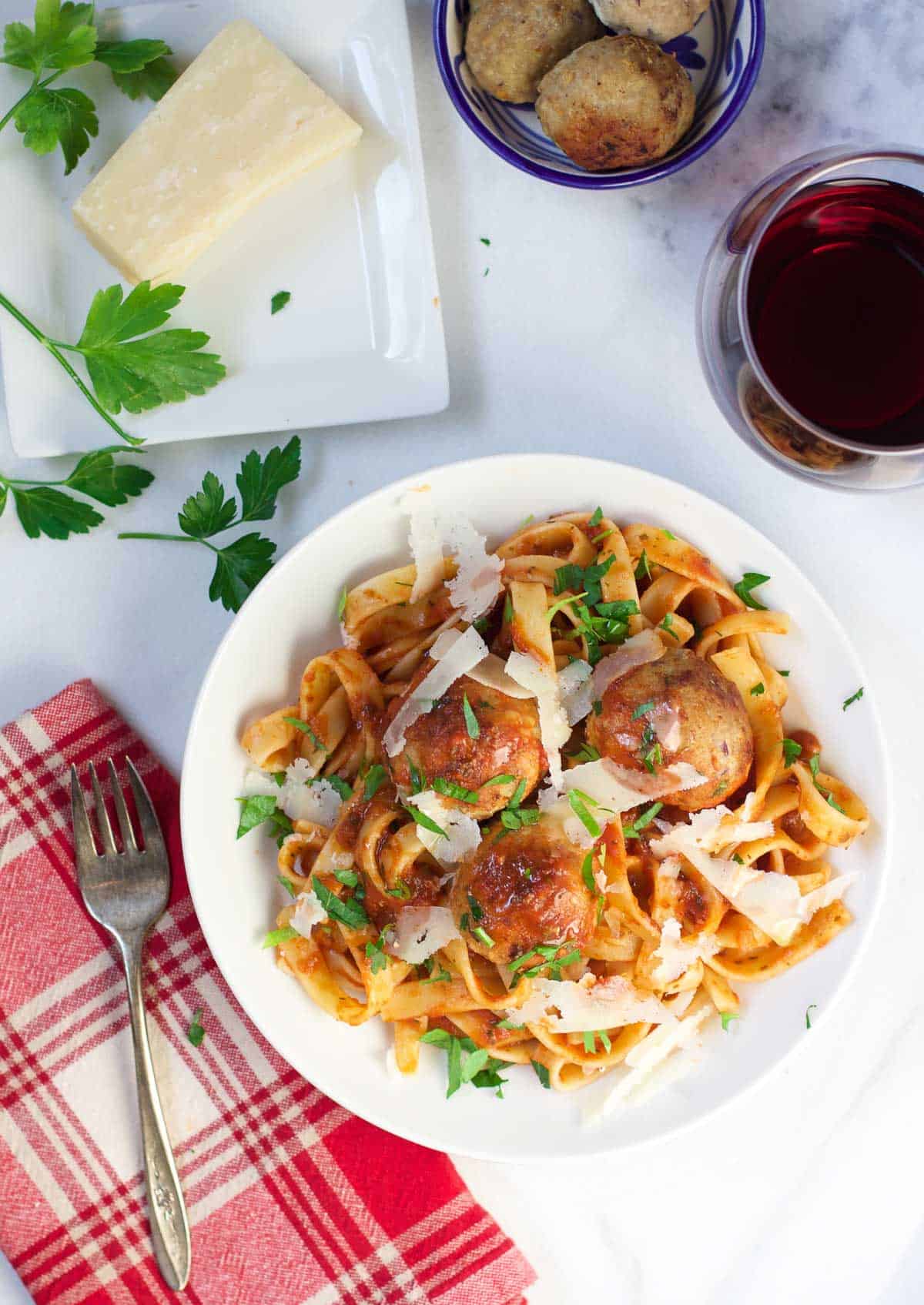 A trencher of pasta with smoked turkey meatballs and a glass of wine