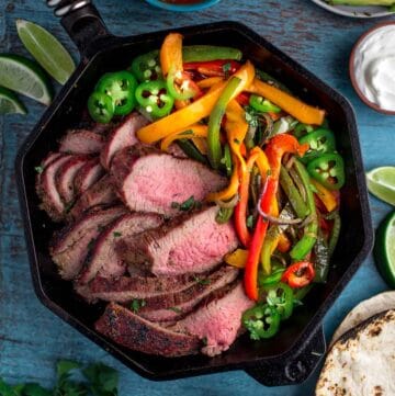 Tri Tip fajitas and peppers in a cast iron skillet.