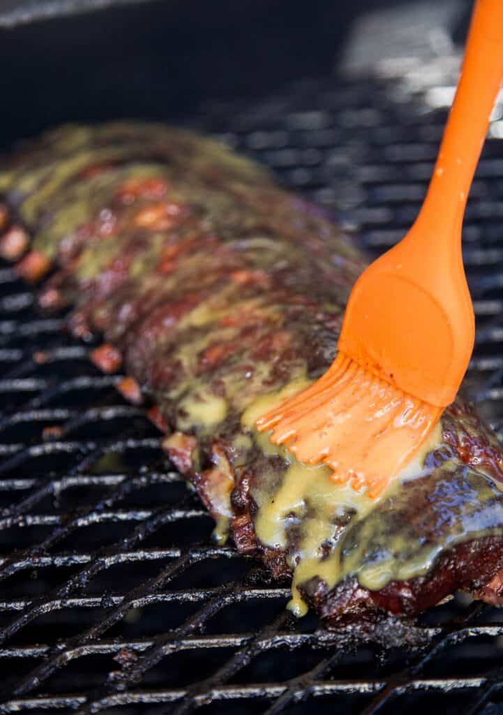 Smoked Honey Mustard Ribs getting glazed with honey mustard sauce