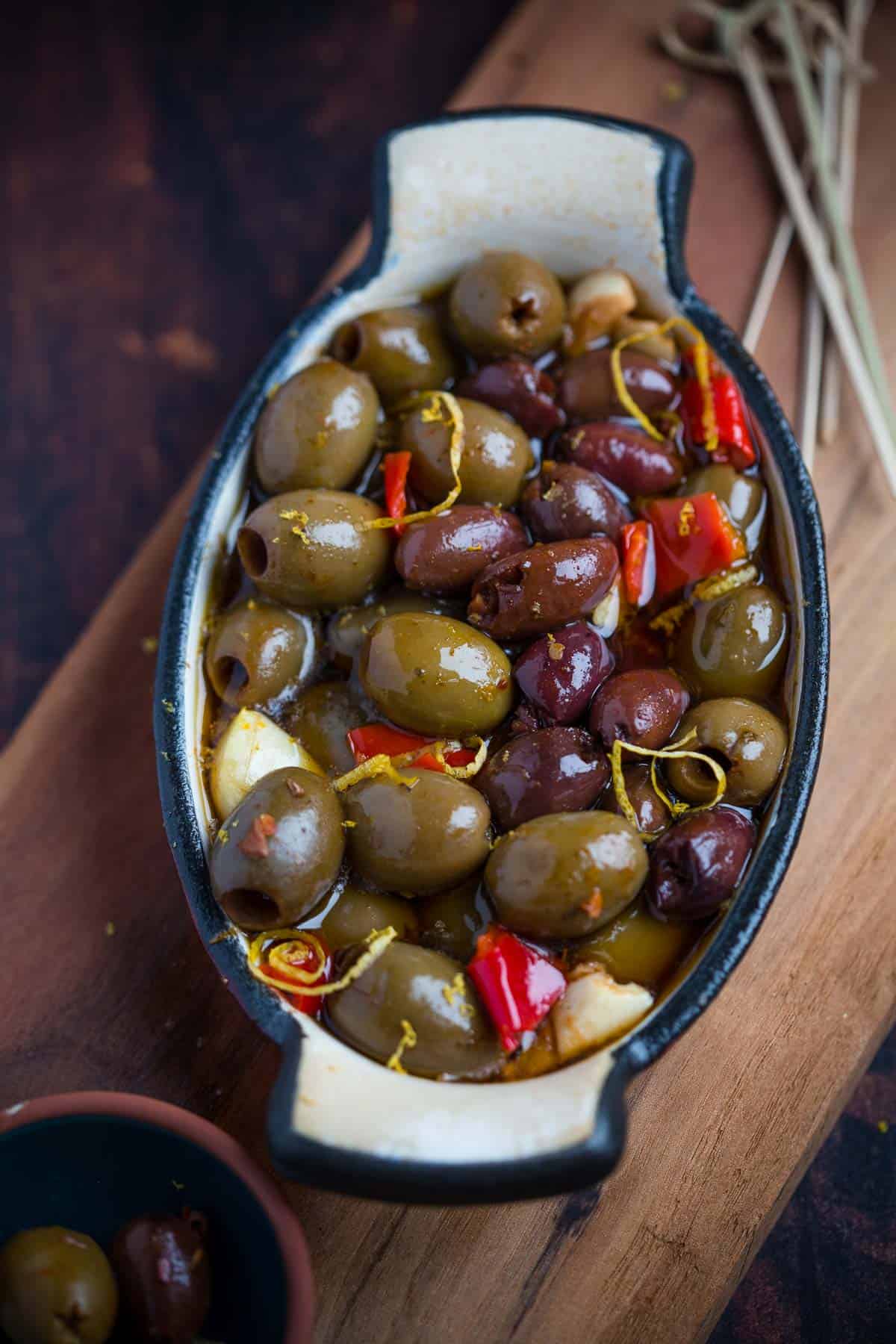 Grilled olives in a baking dish on a cutting board.