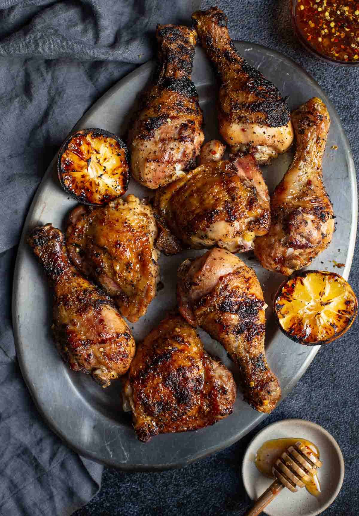 Grilled Hot Honey Chicken on a serving platter with grilled lemon.