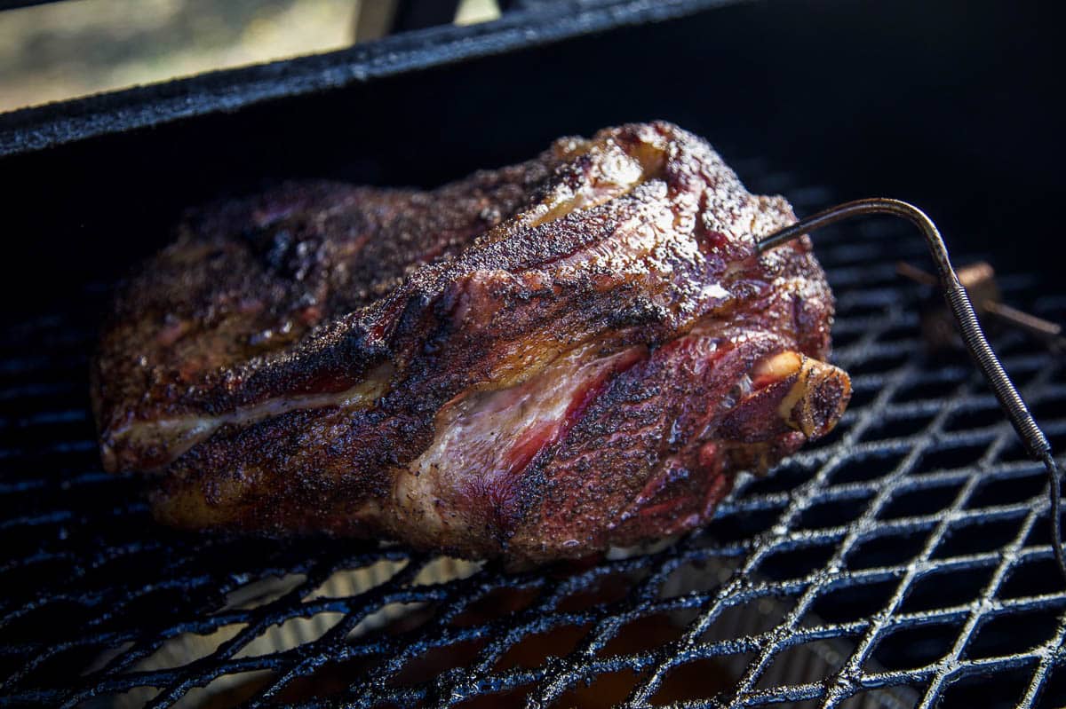 A bone in lamb shoulder cooking on a smoker