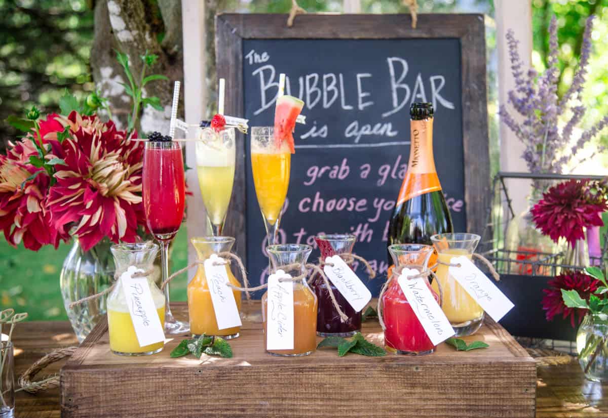 A full mimosa bar spread with mimosa glasses, fresh juices in containers, and sparkling wine 