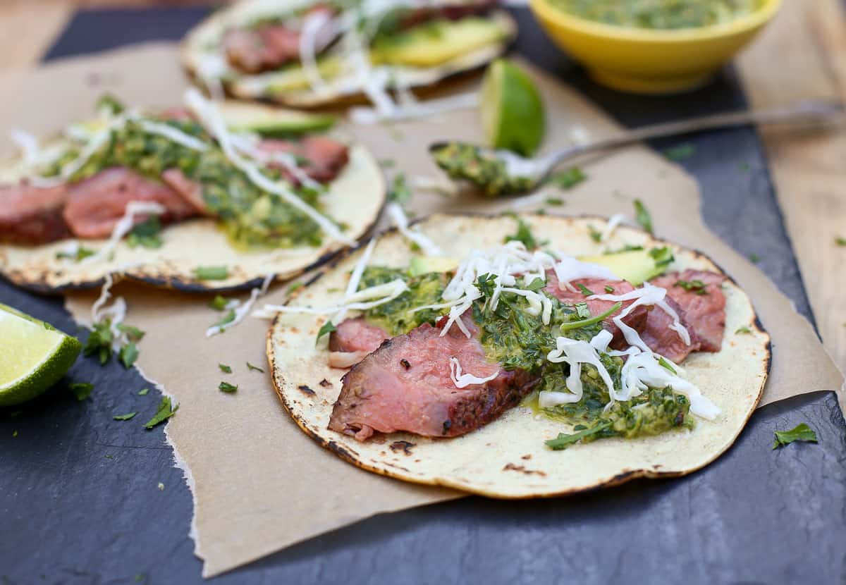 A Grilled Ribeye Steak Taco topped with chimichurri sauce on a platter