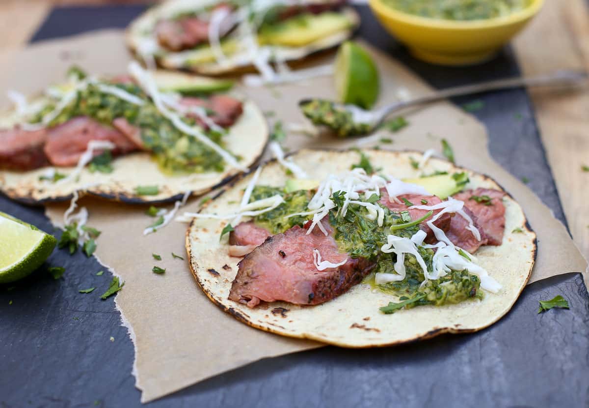  A Grilled Ribeye Steak Taco topped with chimichurri sauce on a platter