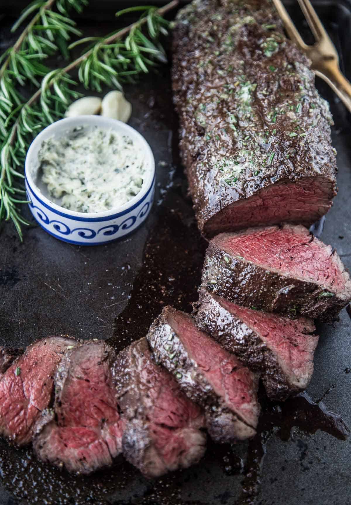 Smoked Beef Tenderloin on a serving dish with some slices cut into thick pieces