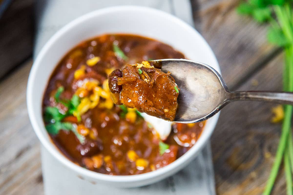 Chili in a bowl with a spoonful of brisket
