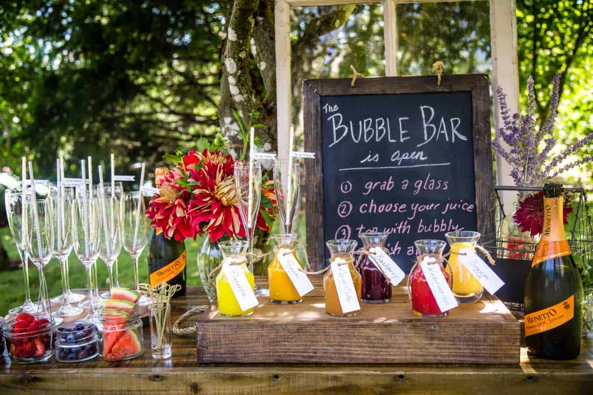 A full mimosa bar spread with juices, fruit garnishes, sparkling wine and mimosa glasses.