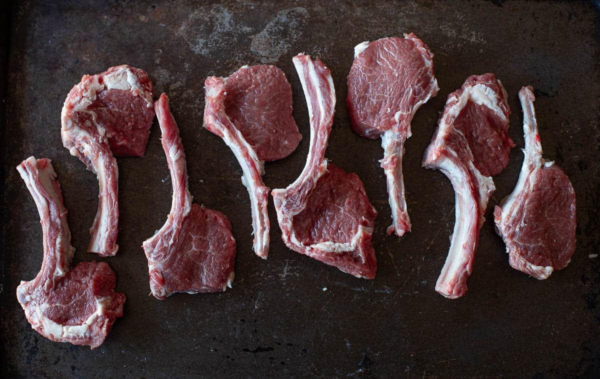 raw lamb chops on a sheet pan