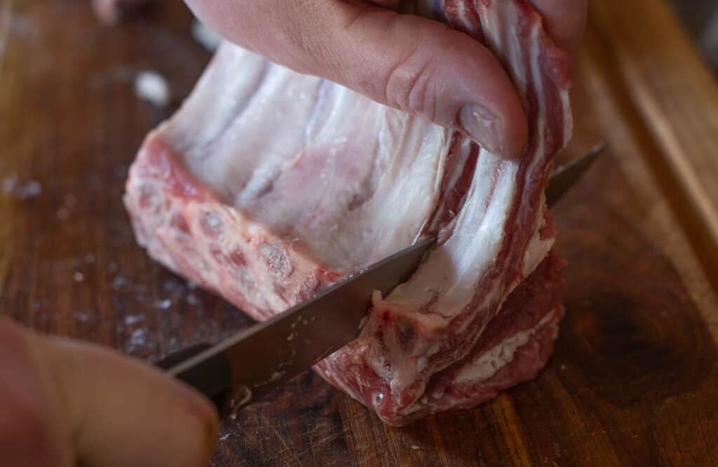 slicing a rack of lamb into lamb chops