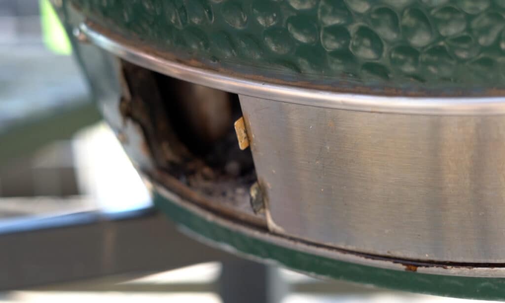 Adjusting the bottom vent of a big green egg.