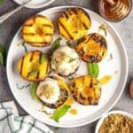 Grilled Peaches topped with ice cream and honey on a serving platter