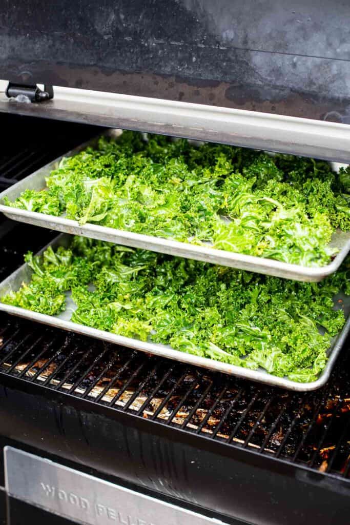 raw kale on a sheetpan cooking in a smoker