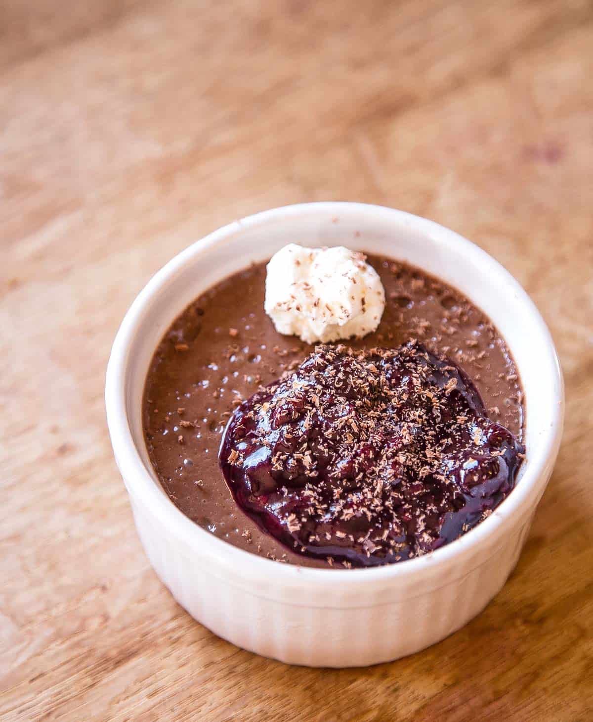 A ramekin filled with Chocolate Pot de Crème with Smoked Oregon Blackberries