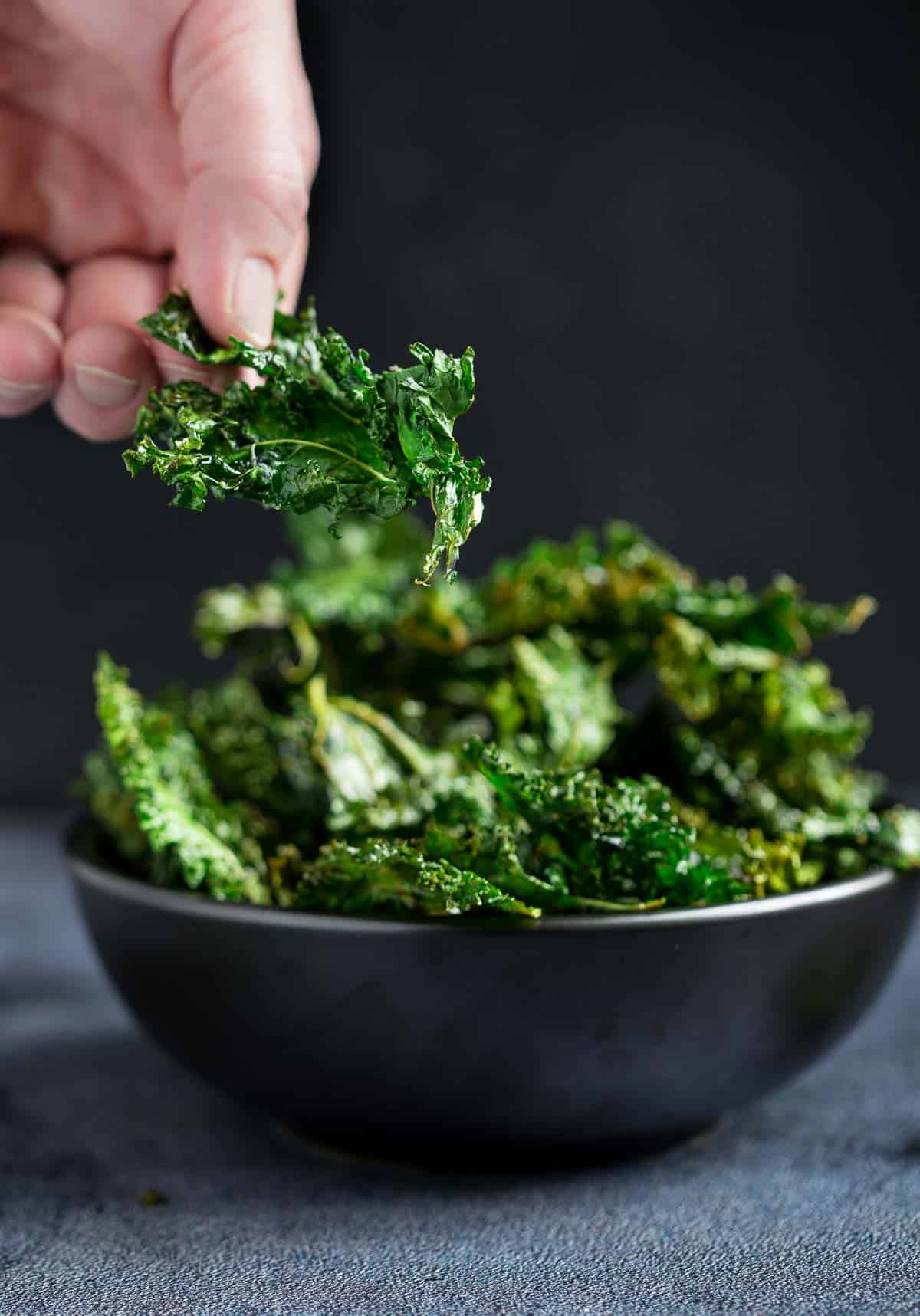 Holding a piece of crispy smoked kale