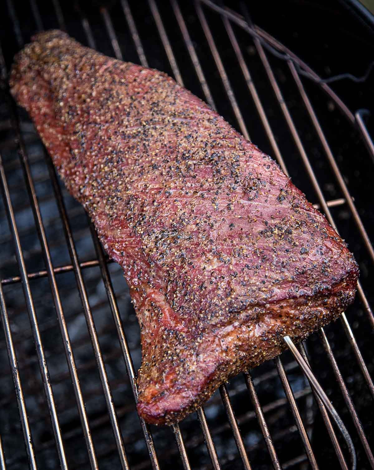 Perfectly smoked Tri Tip, cooked on a Weber Kettle Grill. Tender and delicious! A Tri Tip smoking on a grill