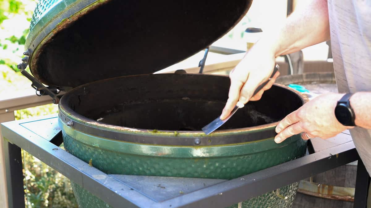 Using a scraper to clean edges of a Big Green Egg before replacing the gasket.