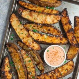 Grilled Potato Wedges on a sheet pan with a bowl of fry sauce